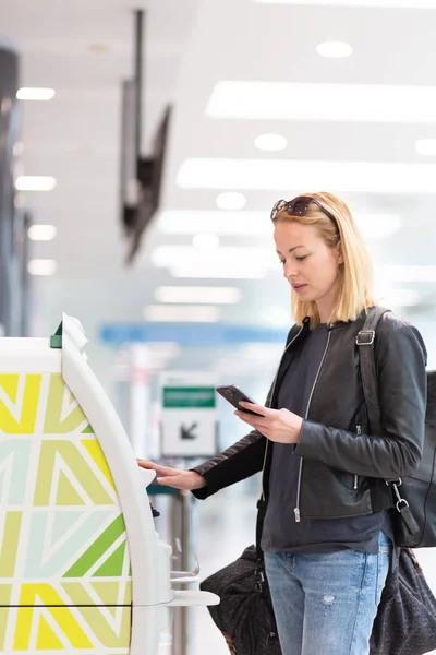 Havaalanında biniş kartı almak akıllı telefon uygulama ve check-in makinesini kullanarak rahat Kafkas kadın. — Stok fotoğraf