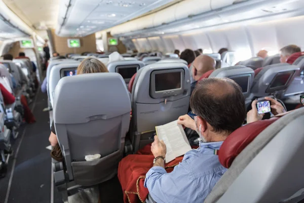 Intérieur du grand avion commercial avec passagers sur leurs sièges pendant le vol . — Photo