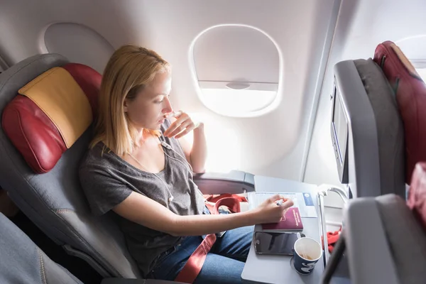 Женщина заполняет иммиграционную анкету на самолете коммерческих пассажиров во время полета . — стоковое фото