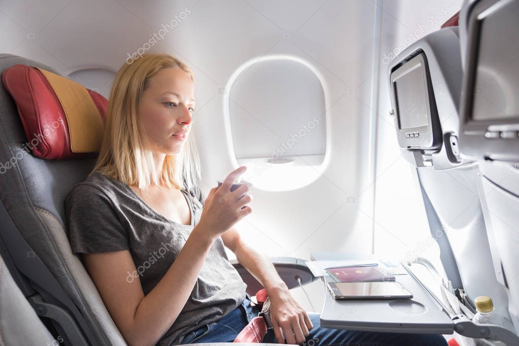 Woman drinking coffee on commercial passengers airplane during flight.