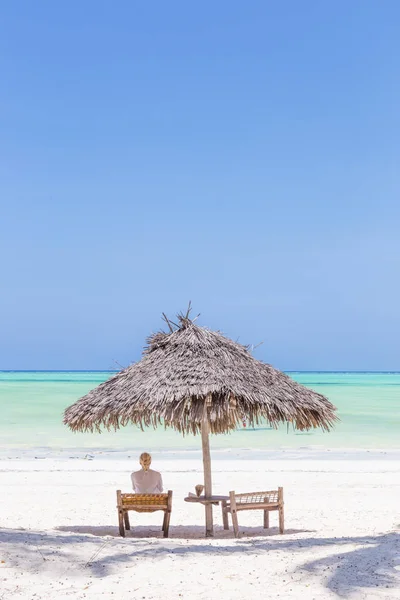 妇女在繁星在热带海滩上的木制伞下的椅子上放松. — 图库照片