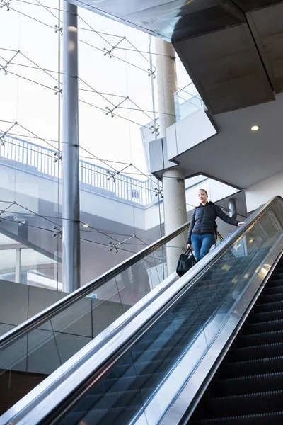 Mujer de negocios con gran bolsa negra y teléfono móvil ascendiendo en escaleras mecánicas . —  Fotos de Stock