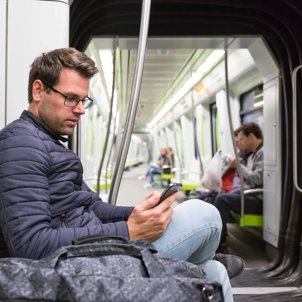 Lectura masculina del viajero desde la pantalla del teléfono móvil en metro. — Foto de Stock