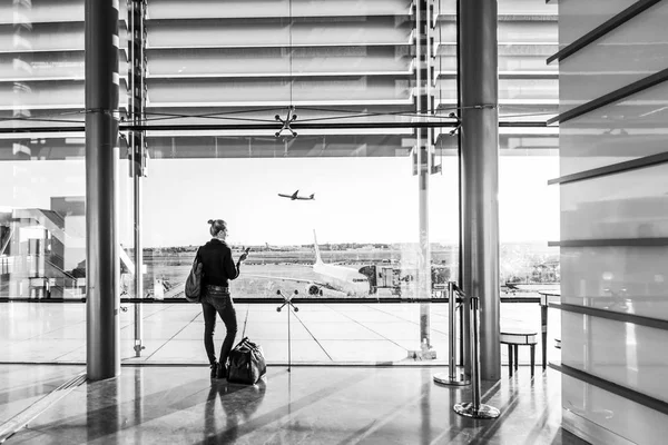Nuori nainen odottaa lentokentällä, katselee portin ikkunasta . — kuvapankkivalokuva