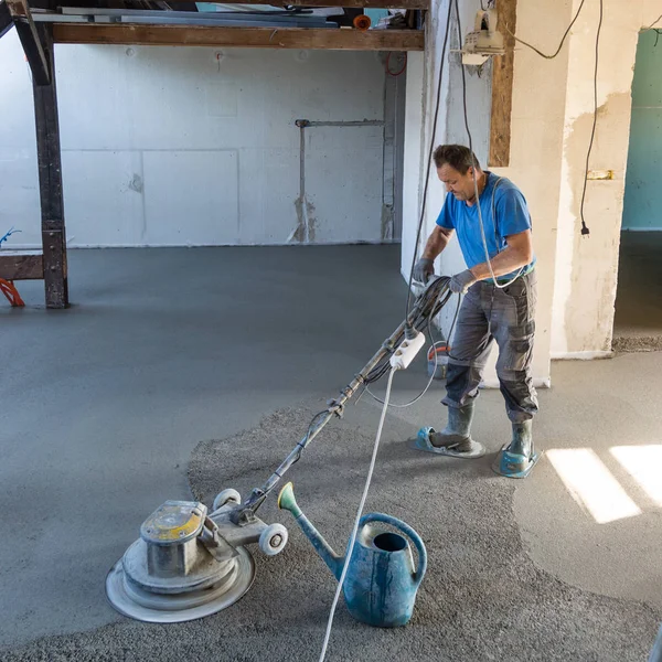 모래를 연마하고 시멘트를 긁어 바닥을 광 내는 기능공. — 스톡 사진