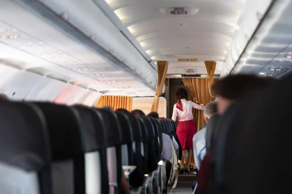 Interior of commercial airplane with stewardess walking the aisle. — Stock Photo, Image
