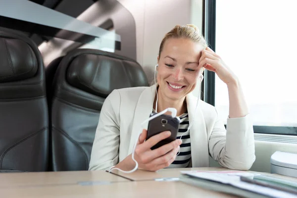 Geschäftsfrau kommuniziert auf Bahnreise per Handy. — Stockfoto