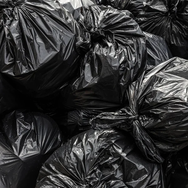 Σωρός από μαύρο πλαστικό κάδο απορριμμάτων τσάντα φόντο. — Φωτογραφία Αρχείου