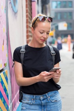 New York city, Amerika Birleşik Devletleri içinde renkli grafiti duvara akıllı telefonlar kullanan kadın.