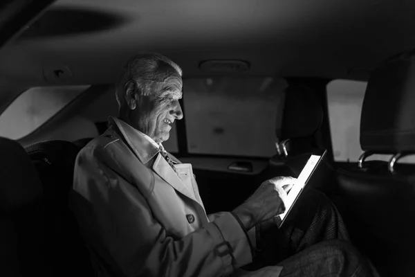 Homme d'affaires avec une tablette numérique assis sur le siège arrière d'une voiture — Photo