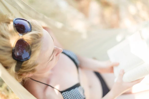 Kvinna läsa bok i hängmattan på stranden — Stockfoto