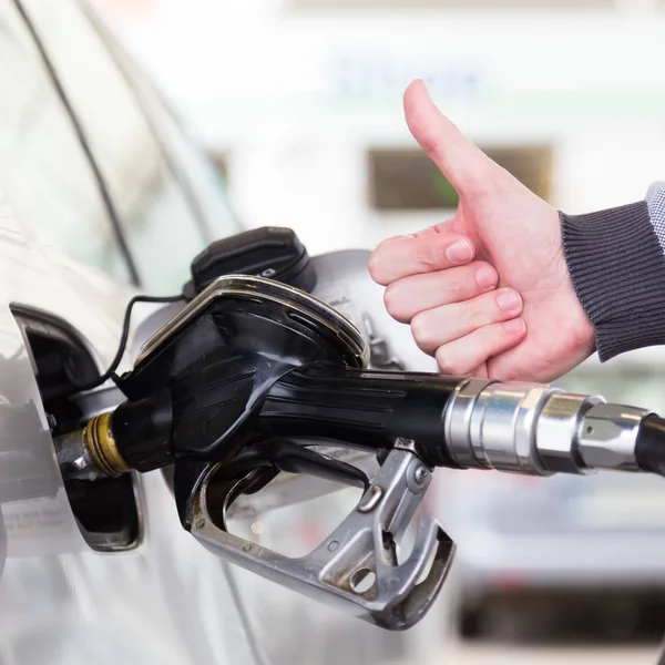ガソリンまたはガソリン自動車車にポンプでくまれます。男は、親指のジェスチャーは、アップを示すガソリン スタンドで自動車にガソリン燃料ポンプのクローズ アップ. — ストック写真