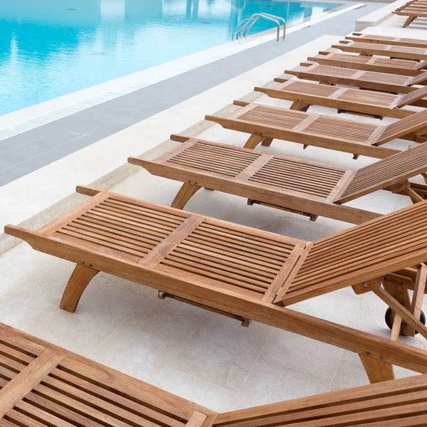Luksusowy basen z drewnianymi krzesełkami. — Zdjęcie stockowe