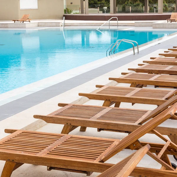 Luxe zwembad met houten ligstoelen. — Stockfoto