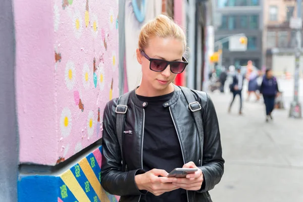 New York şehrinde akıllı telefonu renkli duvar yazılarına karşı kullanan bir kadın..