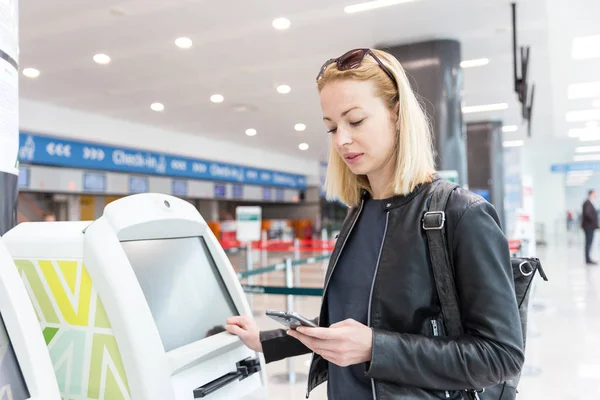 Havaalanında biniş kartı almak akıllı telefon uygulama ve check-in makinesini kullanarak rahat Kafkas kadın.
