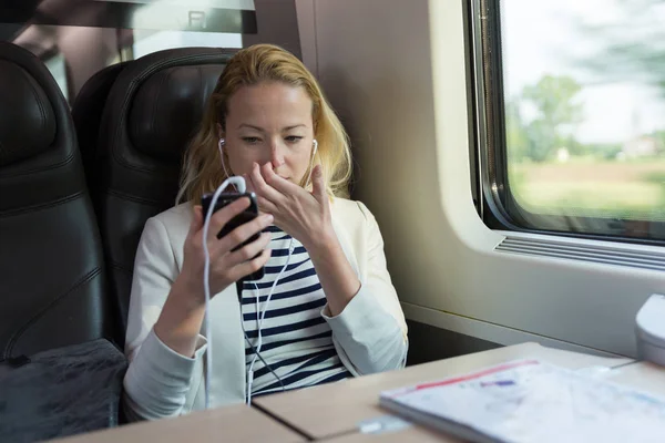 Businesswoman communicating on mobile phone while traveling by train. — Stock Photo, Image