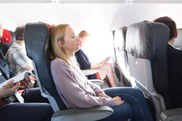 Cansado rubia caucásica casual dama siesta en el asiento mientras viaja en avión. Transporte comercial en aviones. — Foto de Stock