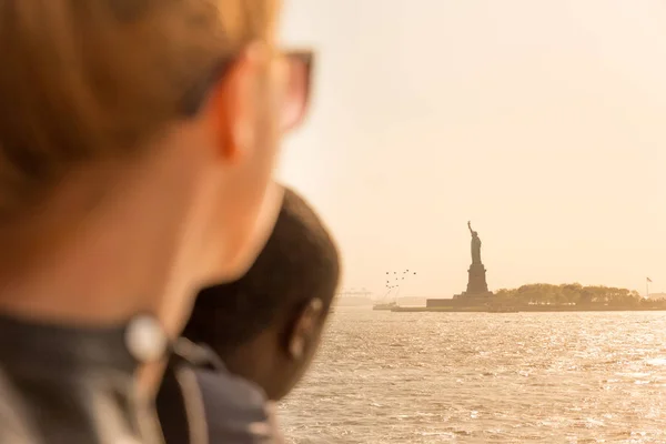 Turistas mirando la silueta de la Estatua de la Libertad al atardecer desde el ferry de la isla de staten, Nueva York, Estados Unidos — Foto de Stock