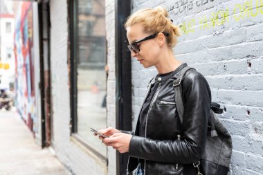 New York şehrinde akıllı telefonu renkli duvar yazılarına karşı kullanan bir kadın..