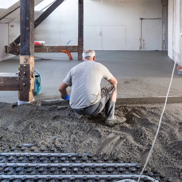Munkás szintező homok és cement esztrich, padlófűtés felett. — Stock Fotó