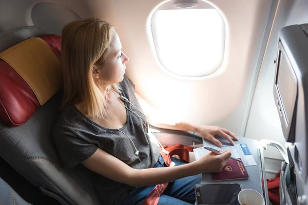 Casual woman flying on commercial passengers airplane, filling in immigration form. — Stock Photo, Image