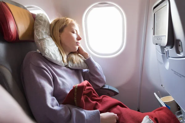 Втомлена блондинка випадкова кавказька леді спить на сидінні під час подорожі літаком. Комерційні перевезення літаками . — стокове фото
