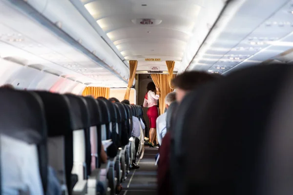 Azafata en uniforme rojo en avión de pasajeros comerciales . —  Fotos de Stock