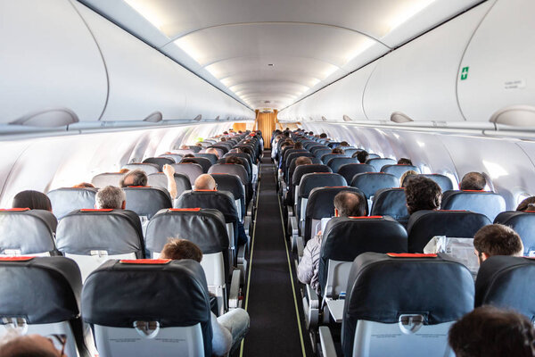 Interior of commercial airplane with passengers on their seats during flight.