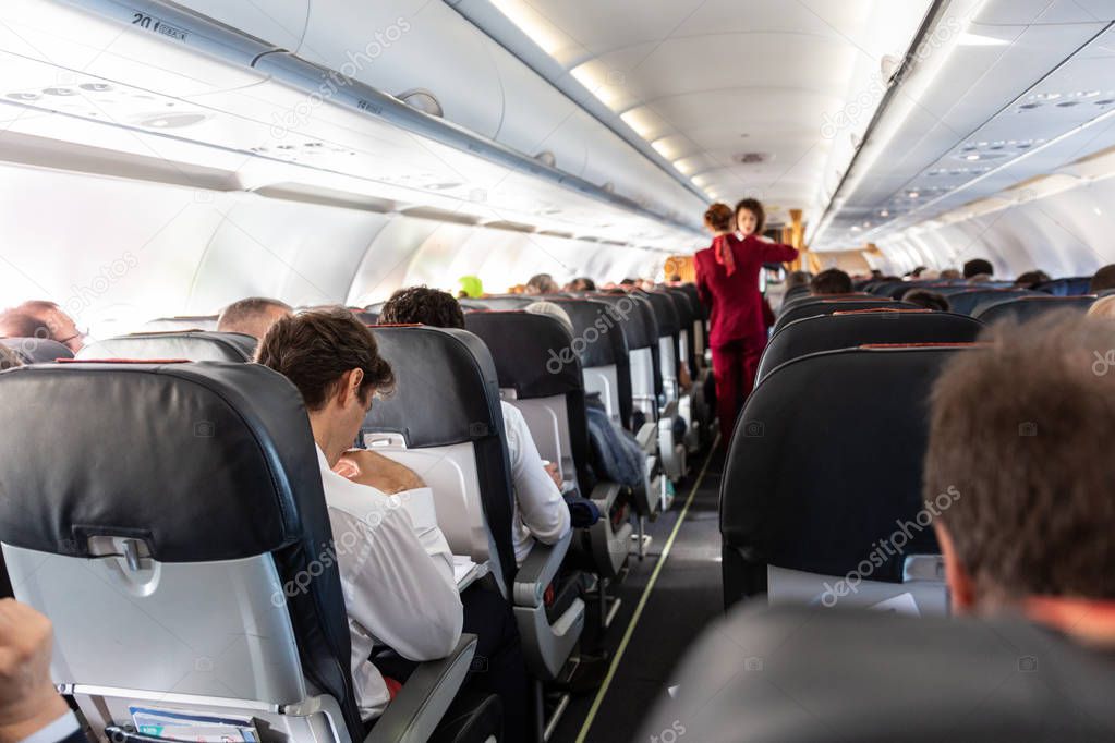 Interior of commercial airplane with passengers on their seats during flight.