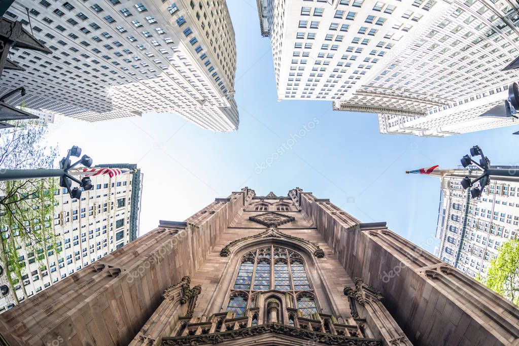 Wide angle upward view of Trinity Church at Broadway and Wall Street with surrounding skyscrapers, Lower Manhattan, New York City, USA