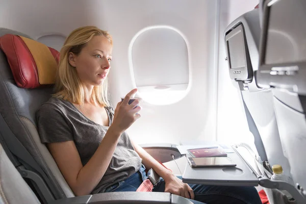 Woman drinking coffee on commercial passengers airplane during flight.