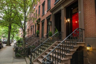 Row of old brownstone buildings along an empty sidewalk block in the Greenwich Village neighborhood of Manhattan, New York City NYC clipart