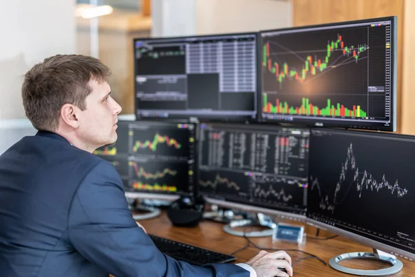 Aktienhändler blickt im trendigen Büro auf Computerbildschirme. — Stockfoto