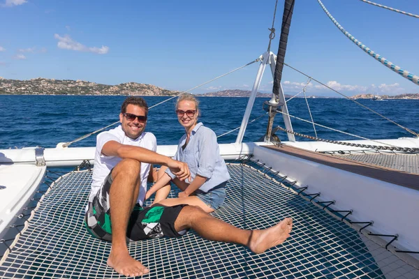 Romantic couple relaxing on a summer sailin cruise, sitting on a luxury catamaran, sailing in Maddalena Archipelago, Sardinia, Italy.