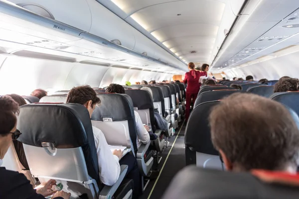 Interno di un aereo commerciale con passeggeri ai loro posti durante il volo . — Foto Stock