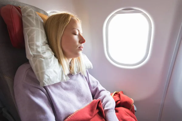 Tired blonde casual caucasian lady napping on seat while traveling by airplane. Commercial transportation by planes. — Stock Photo, Image