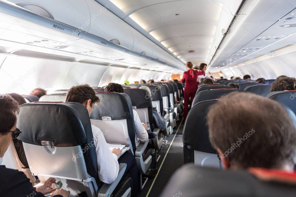 Interior of commercial airplane with passengers on their seats during flight.