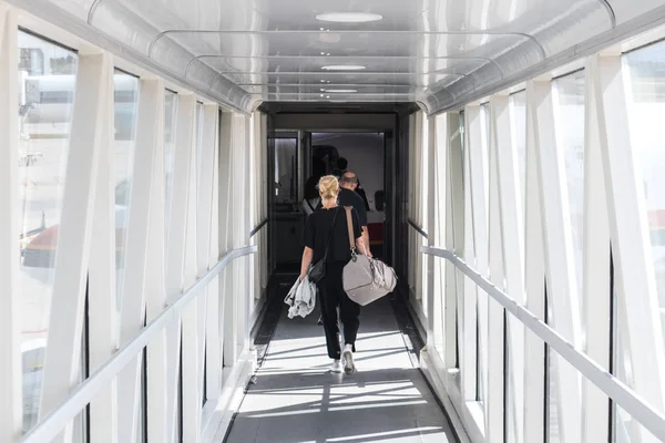 Pasajera que lleva el equipaje de mano, caminando por el pasillo de embarque del avión . —  Fotos de Stock