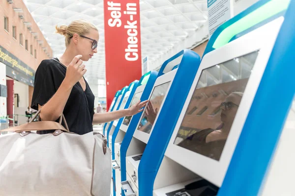 보 딩 패스를 받고 공항에 스마트폰 응용 프로그램 및 체크인 기계를 사용 하 여 캐주얼 백인 여자. — 스톡 사진