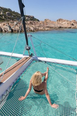 Bir yaz yelkenli gezisinde bronzlaşan ve dinlenen kadın, lüks katamaran hamağında uzanan Spargi adasında mükemmel beyaz kumlu plaj, Maddalena Archipelago, Sardunya, İtalya.