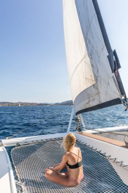 Kadın cruise yelken, resim mükemmel Palau town, Sardunya, İtalya yakınındaki bir Lüks Katamaran üzerinde oturan bir yaz üzerinde rahatlatıcı.