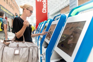 Havaalanında biniş kartı almak akıllı telefon uygulama ve check-in makinesini kullanarak rahat Kafkas kadın.