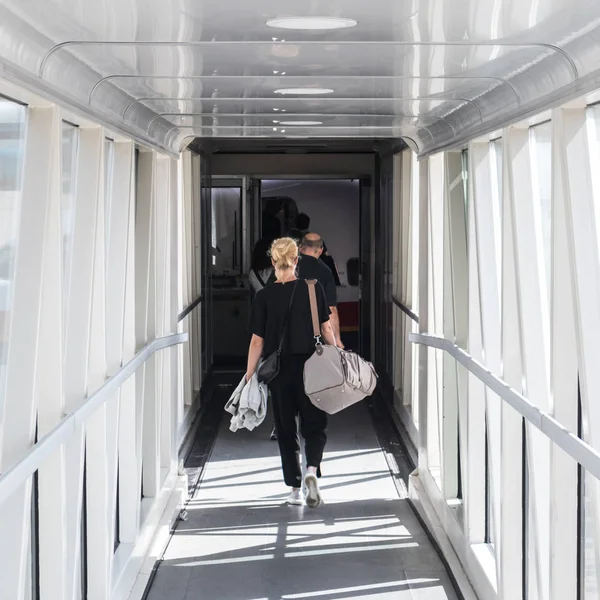 Passageiro fêmea carregando o saco de bagagem de mão, caminhando pelo corredor de embarque do avião . — Fotografia de Stock