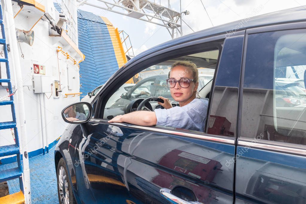 Female driver parking her car on ferry boat on trip to their summer vacations island destination. Sardinia, Italy