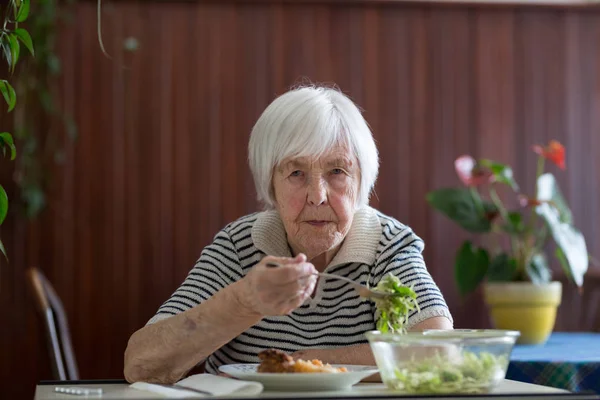 Solitary senior woman eating her lunch at retirement home.