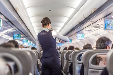 Uçuş sırasında koltuklarda servis yapan hostesli ticari uçağın içi..