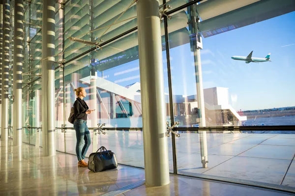 Giovane donna in attesa in aeroporto, guardando attraverso la finestra del cancello . — Foto Stock