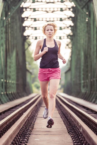 活跃的女运动员在铁轨上跑步. — 图库照片