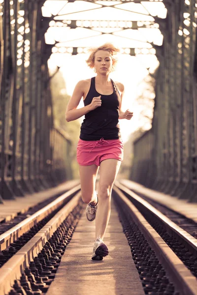 活跃的女运动员在铁轨上跑步. — 图库照片